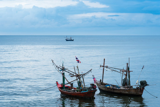Fishing boats floating in the sea over cloudy sky at Prachuap Khiri Khan, Thailand.