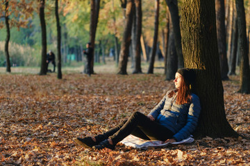 Autumn woman under tree in autumn park