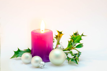 Obraz na płótnie Canvas Christmas ornaments, purple candle with white christmas spheres and green holly