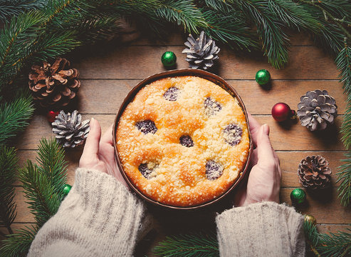 Female hands holding Christmas pie on wooden table