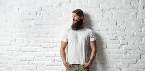 Trendy young bearded man against white brick wall