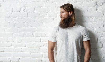 Obraz premium Trendy young bearded man against white brick wall
