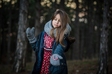 Girl in a forest with candy cane waiting for Christmas