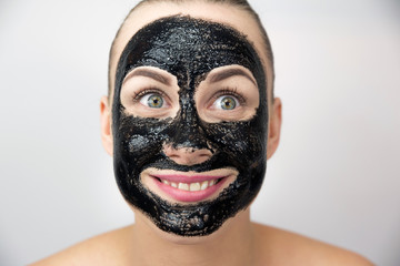 Woman with purifying black mask on her face 
