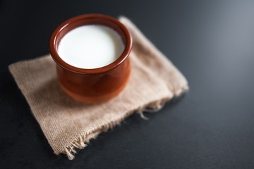 Sour  cream or natural  Cottage cheese curd in clay pot on dark  background. Traditional Cuajada yogurt cream