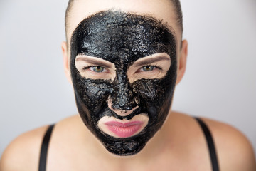 Woman with purifying black mask on her face 
