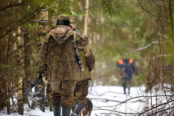 Hunter in camouflage with rifle. Winter hunting.