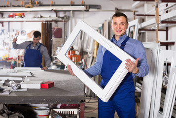 Production workers in coverall with different   finished PVC profiles and windows at factory