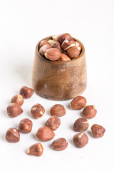 Raw hazelnuts in the wooden cup isolated above white background