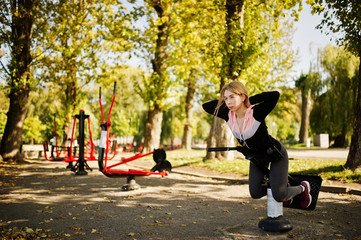 Young girl has the training and doing exercise outdoors on street simulators. Sport, fitness, street workout concept.