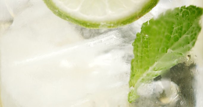 closeup of coctail. Mojito, tonik water with mint and lemon and lime and ice cubes closeup buubles ice texture