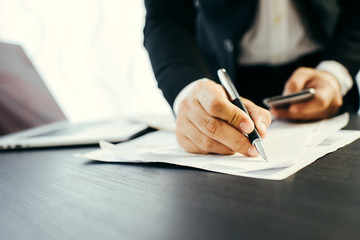 Side view shot of a man's hands using smart phone in interior, rear view of business man hands busy using cell phone at office desk