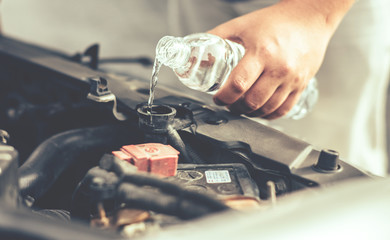 Mechanic repairing car with open hood,Side view of mechanic checking level motor oil in a car with open hood