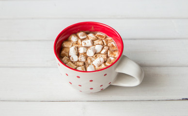 Hot chocolate in red cup on white wooden background