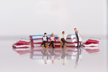 Fototapeta premium Miniature people sitting on book using as background education or business concept