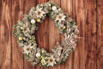 Christmas wreath with natural decorations hanging on a rustic wo