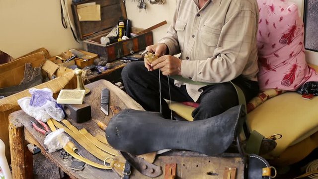 Saddler. Saddle manufacture. Leather goods craftsman at work in his workshop. Artisan Leather. Saddle crafting. Old vintage art. Traditional sewing leather to the point of saddle. Azerbaijan old art.
