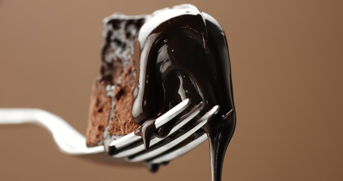 closeup of piece of chocolate cake on a fork with a liquid topping