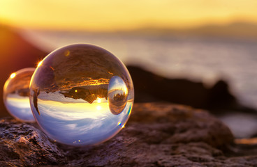 Crystal Ball Reflection on the seashore in sunrise light. Mirror reflections in two crystal balls