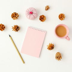 Feminine desktop with golden pine cones, pink notebook, coffee c
