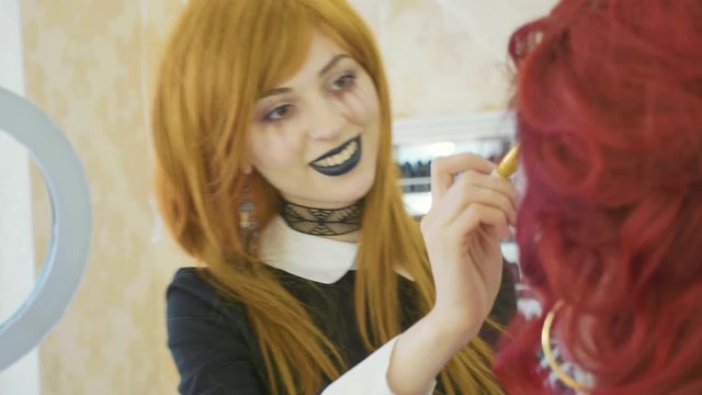 Artist with halloween makeup applying halloween makeup on model's face.