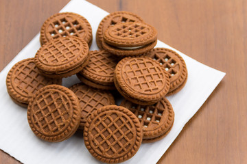 Chocolate cookies with cream filling on wooden table