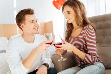Beaming young couple drinking red wine at home