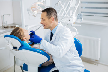 Obraz na płótnie Canvas Positive cheerful doctor sitting near the patient