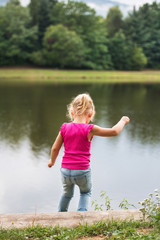 Fototapeta na wymiar Little girl in the nature by the lake.