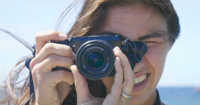 A female tourist photographer is taking pictures, with a backpack on her back, a wonderfully beautiful view of the blue sea and sky. Concept: travel, vacation, photo camera, photo courses, lifestyle.