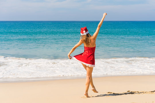 Beautiful happy woman in Mrs. Claus custume on tropical beach, Christmas  and new year vacations concept.