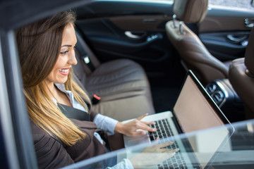 Beautiful business woman working on laptop in a limousine