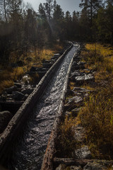 Obraz premium A beautiful autumn scenery of a historic water channel for transporting timber between lakes. Wooden construction. Autumn in Femundsmarka National Park.