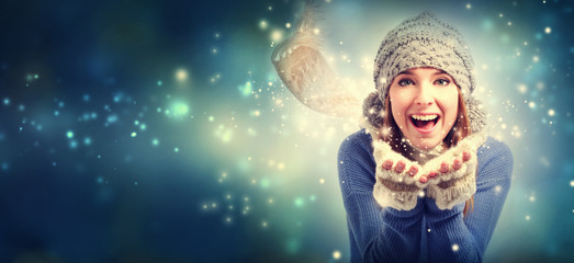 Happy young woman blowing snow in snowy night