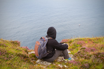 Man sits on the edge of cliff enjoying sea view, horizontal