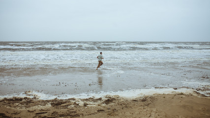 Man running along the seashore in stormy weather