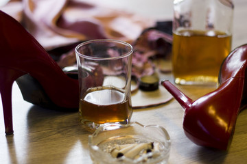 sexy lingerie, high heels, a glass and a bottle of alcohol, ashtray with cigarettes