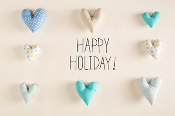 Happy Holiday message with blue heart cushions on a white paper background