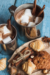 Metal cups with cacao and marshmallow and different cookies