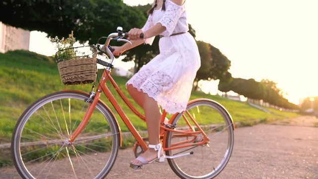 Young beautiful woman standing near her bicycle at sunset. Slow motion