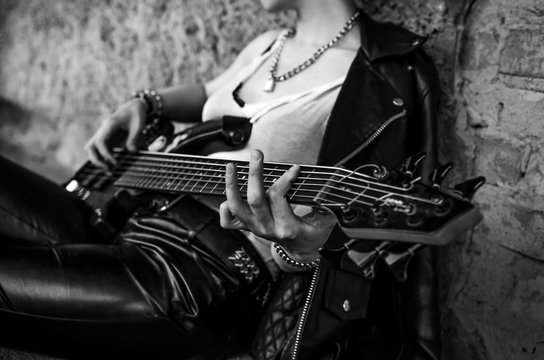 Close-up photo of electric guitar player in leather jacket. Black and white photo