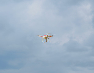 Fototapeta na wymiar Small white quadcopter flying in the sky, drone flight with wireless remote control technology