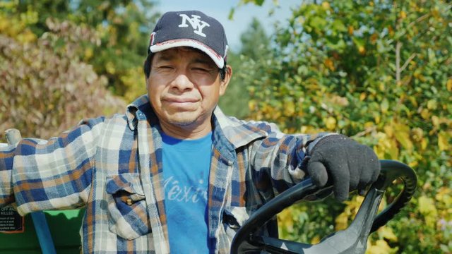 A Mexican worker is sitting behind the wheel of a small tractor.