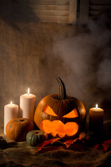 Scary jack-o-lantern, red leaves and candles
