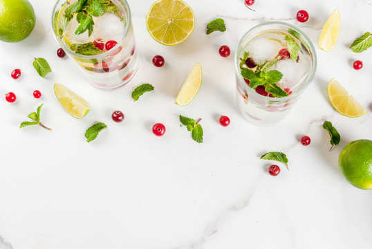 Fall and winter refreshment drink, cranberry mojito cocktail with lime and mint, on white table, copy space top view