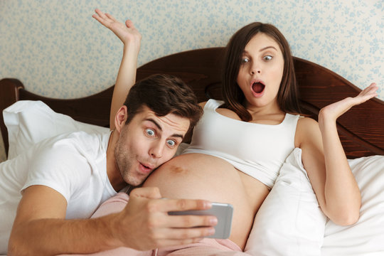 Funny happy young pregnant couple taking selfie