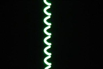 Green letter C symbols on black background due to long exposure time and camera shake