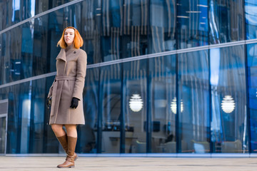 Business girl with. against the backdrop looks directly at the camera. of a business city with glass. he's going to work businesswoman