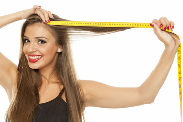 young happy beautiful woman measured her hair with a measuring tape
