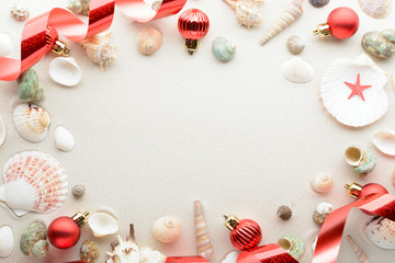 Festive Christmas card. Balls and seashells on sand with copy space